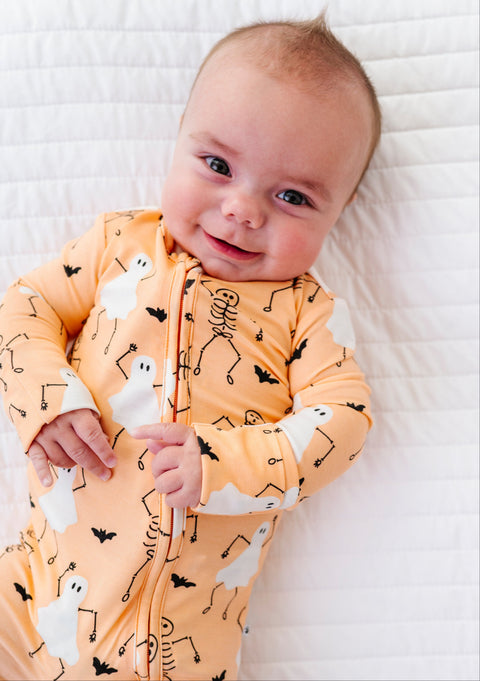 Baby wearing a Halloween-themed onesie on a white blanket