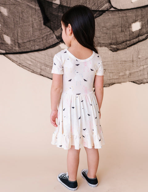Young girl wearing a white dress with black patterns on a beige background