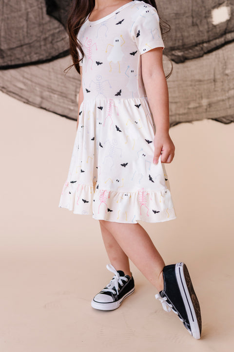 Child wearing a white dress with black and pink butterfly pattern on a beige floor.