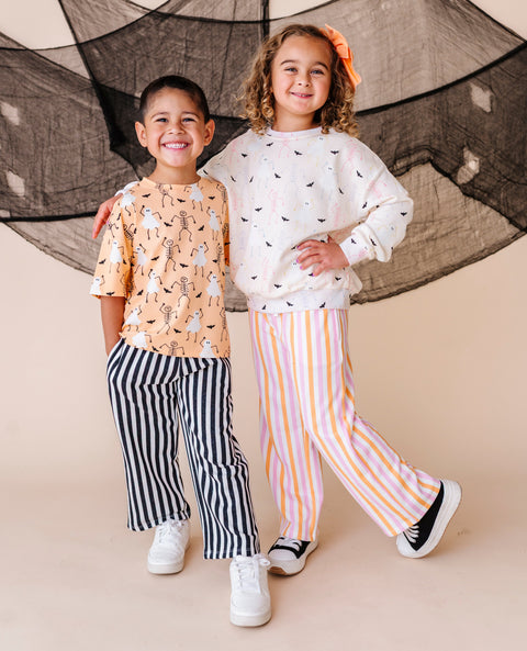 Two children standing together in front of a decorative net on a beige background