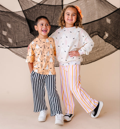 Two children standing in front of a decorative net against a beige background