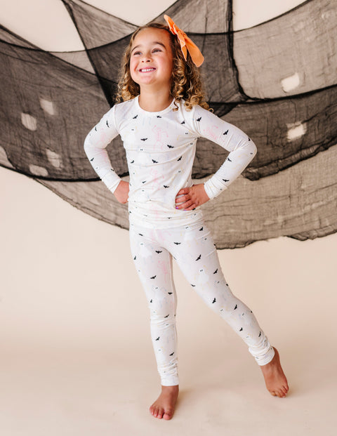 Child wearing a cream pajama set with halloween patterns in front of a large net.