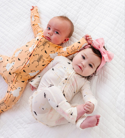 Two babies in pajamas lying on a textured white surface