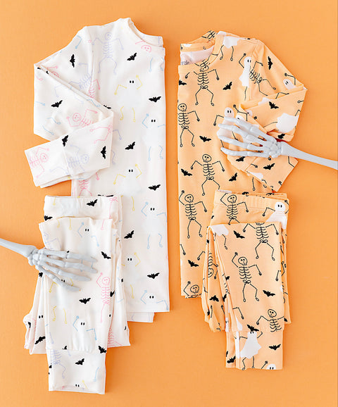Children's Halloween-themed pajama sets with skeletons and bats on an orange background